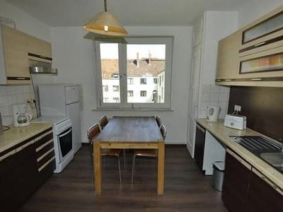 Küche mit dunklen Unter- und hellen Oberschränken mit Essbereich in der Mitte