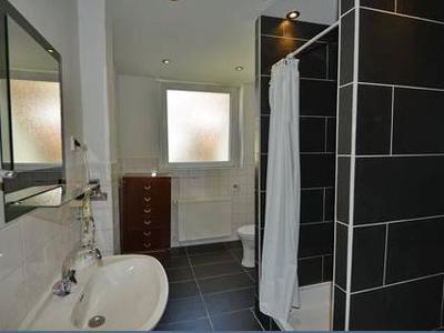 Tageslichtbad mit dunklen Fliesen und großer Dusche mit Duschvorhang