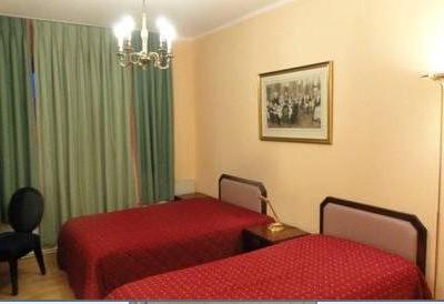 Zweibettzimmer mit grünen Vorhängen und roten Tagesdecken auf den Betten