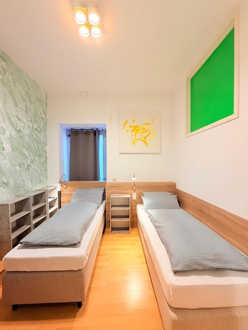 Schmales Schlafzimmer mit zwei Einzelbetten, Nachttisch in der Mitte und Holzfußboden