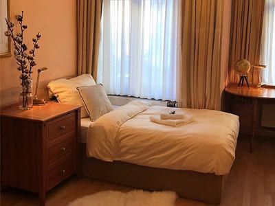 Gemütliches Einzelzimmer mit Holzmöbeln und Vorhängen