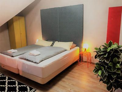 Doppelzimmer im Hotel mit gepolsterter Rückwand hinter dem Bett und einem abstrakten Teppich vor dem Bett