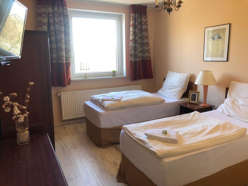 Zweibettzimmer mit gemusterten Vorhängen und dunklen Holzmöbeln