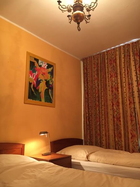 Zweibettzimmer mit gemusterten Vorhängen und orangener Wandgestaltung