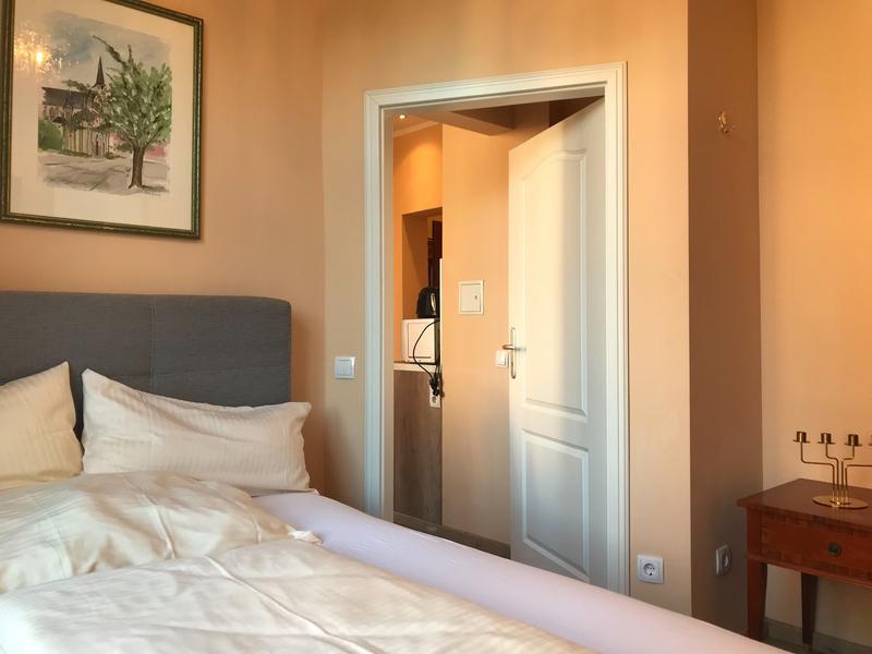 Schlafzimmer mit warmer Wandfarbe und Blick durch die Tür in den Rest der Wohnung