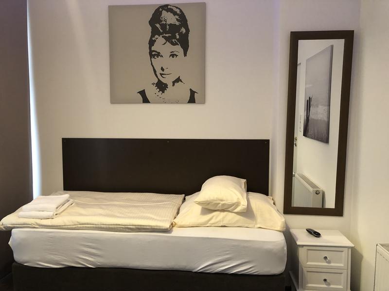 Schlafzimmer mit dunklem Bett und großem Spiegel