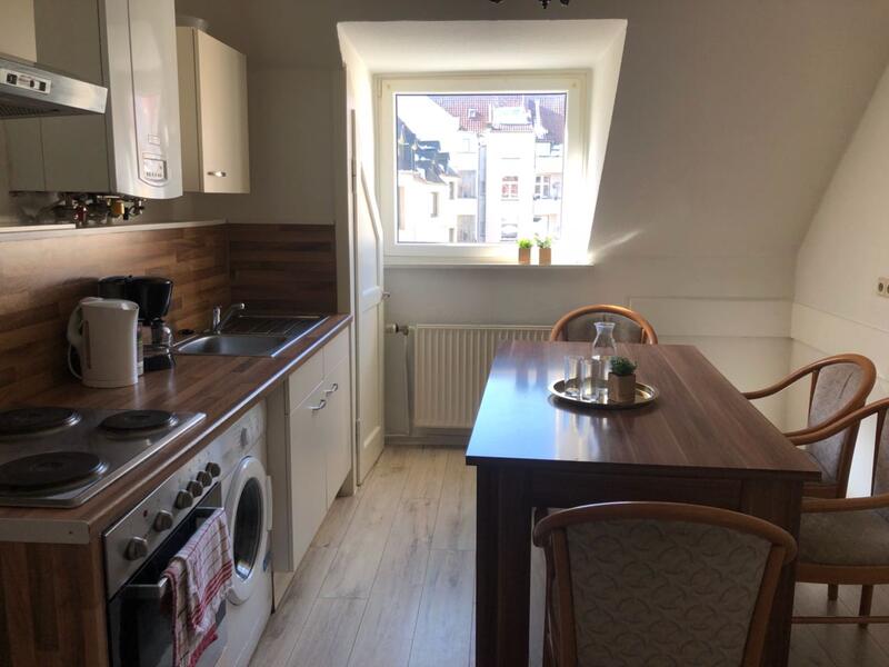 Helle Küche einer Dachgeschosswohnung mit Waschmaschine und Sitzplatz