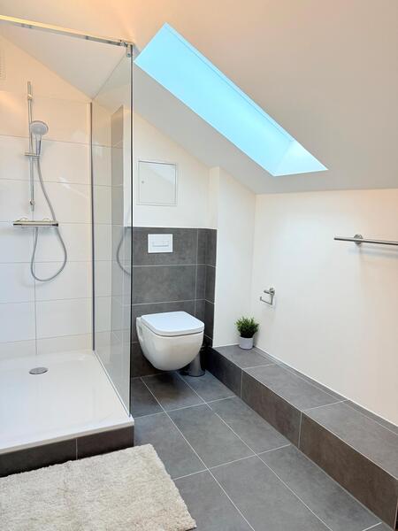 Bad mit Dachschräge und dunkelgrauen Fliesen