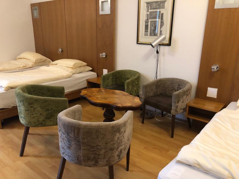 Pokój wieloosobowy z częścią wypoczynkową pośrodku między łóżkami