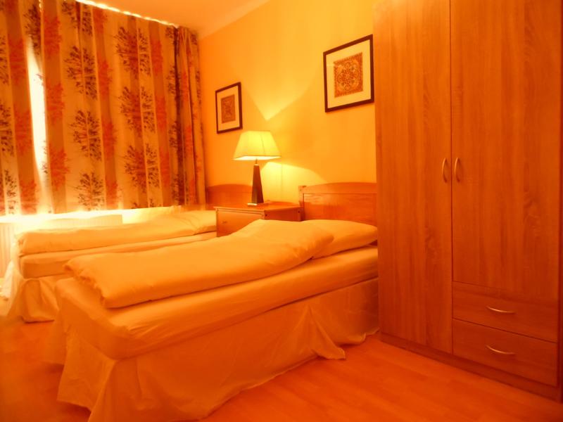 Zweibettzimmer mit gemusterten Vorhängen und Kleiderschrank