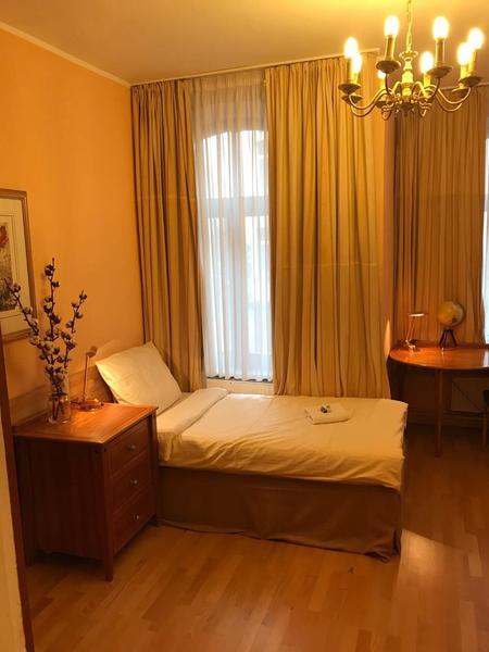 Gemütliches Einzelzimmer mit warmer Wandfarbe und Holzmöbeln und Kronleuchter