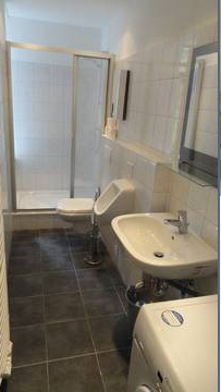 Bad mit dunklen Bodenfliesen und weißen Wandfliesen