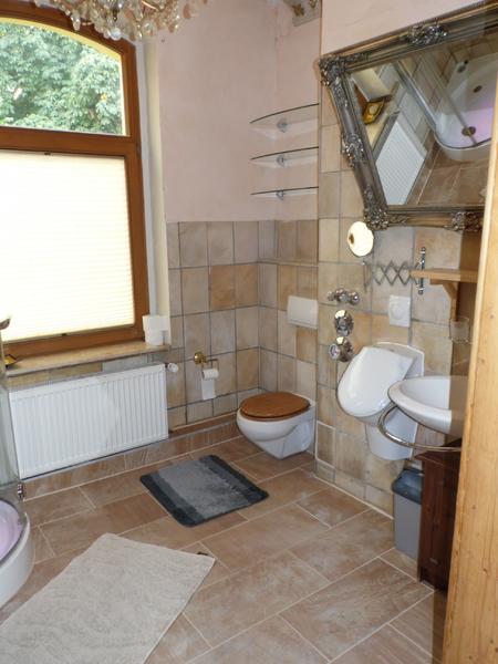 Badezimmer mit Rundbogenfenster und braunen Fliesen