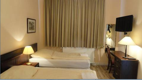 Zweibettzimmer mit Fernseher und Schreibtisch