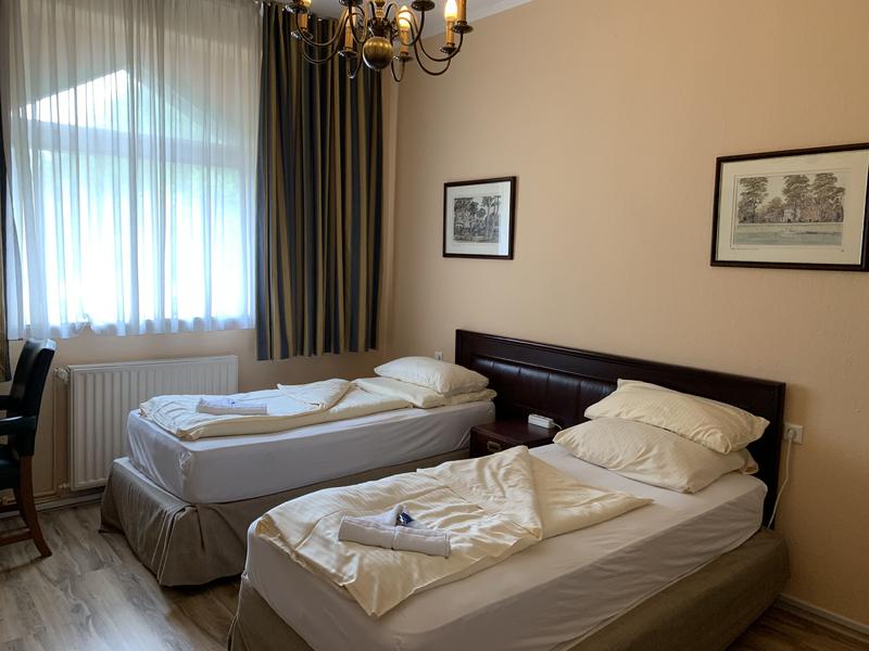 Zweibettzimmer mit großem Fenster und Kronleuchter