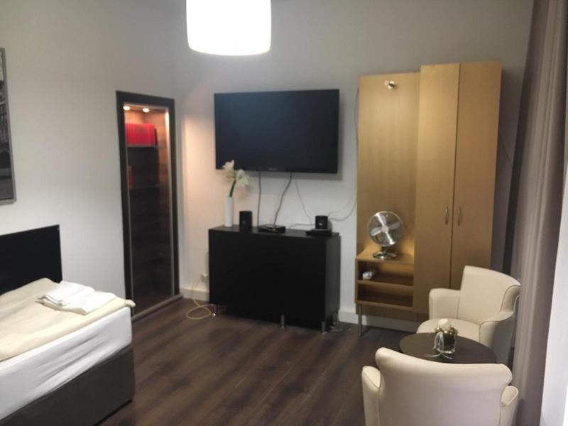 Einzelzimmer mit Fernseher und Sitzbereich mit hellen Ledermöbeln