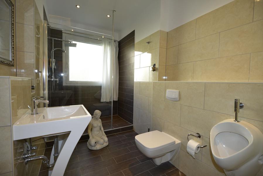 Helles Badezimmer mit dunklen Bodenfliesen und großer Dusche