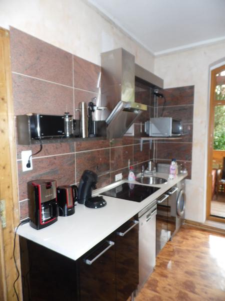 Schwarze Hochglanz-Küchenzeile mit weißer Arbeitsplatte und roten Marmorwandfliesen