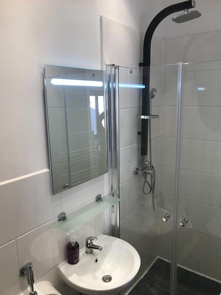 Kleines Bad mit hellen Fliesen an der Wand und dunklen Bodenfliesen