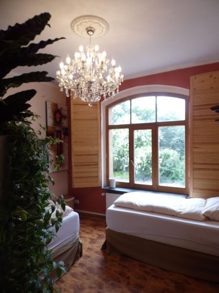 Zweibettzimmer mit Kronleuchter und Rundbogenfenster
