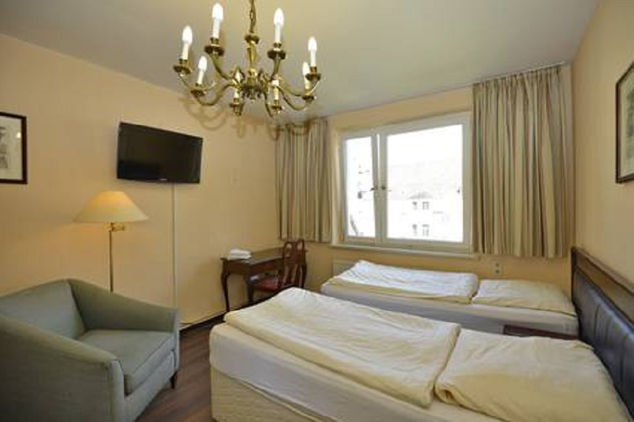 Helles Zweibettzimmer mit Stuhl in der Ecke