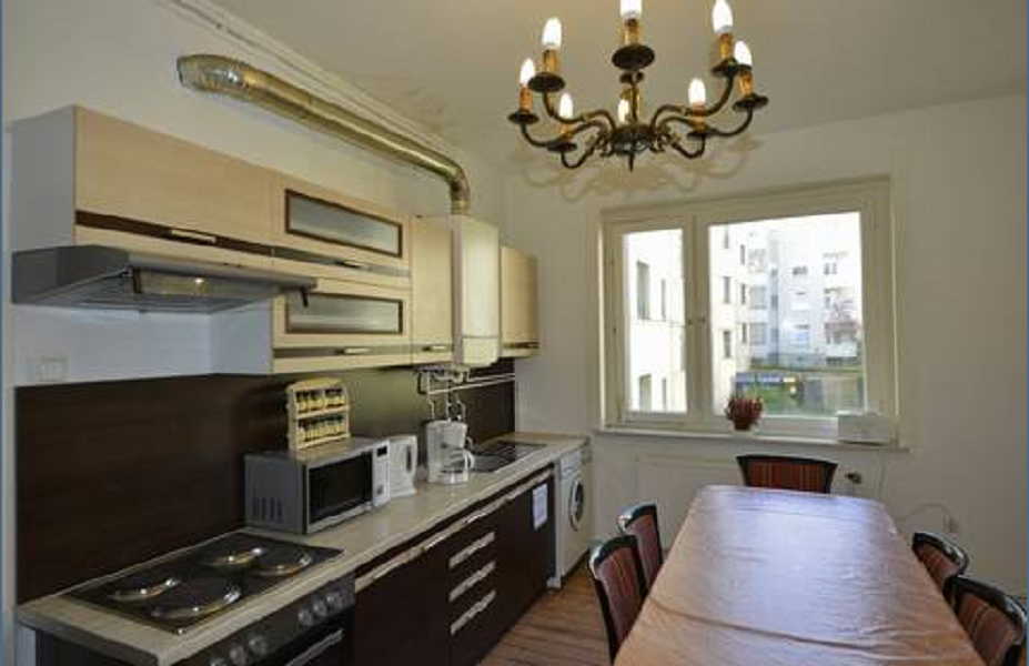 Dunkle Küchenzeile mit gellen Oberschränken und großem Esstisch mit Stühlen