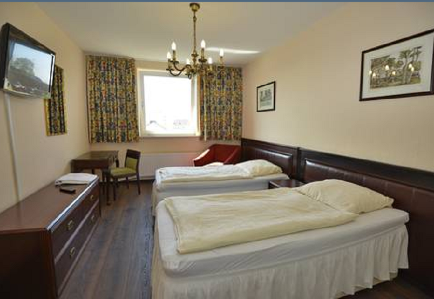 Zweibettzimmer mit gemusterten Vorhängen und Fernseher