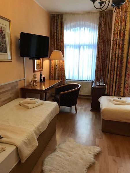 Gemütliches Zweibettzimmer mit gemusterten Vorhängen und Holzboden