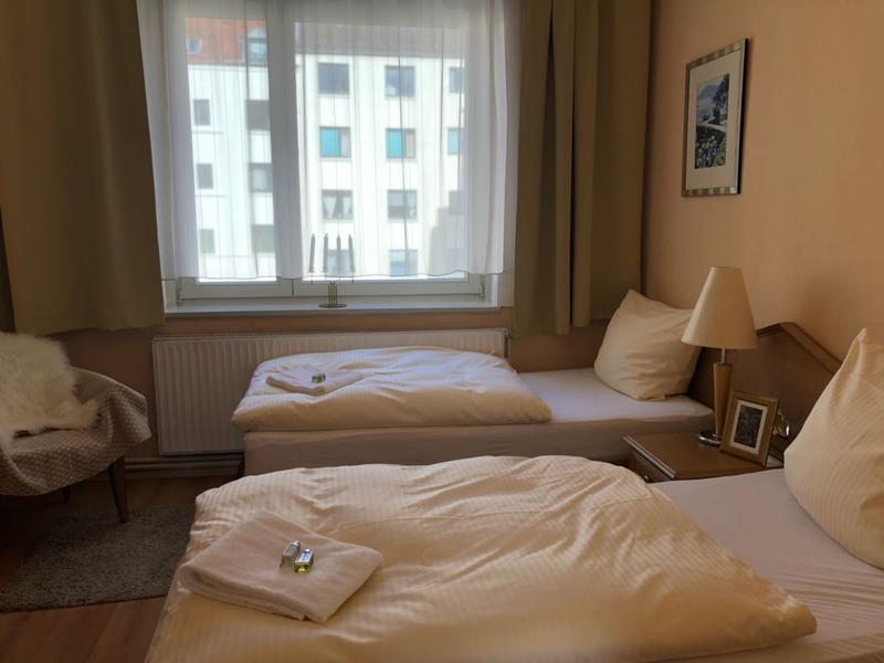 Zweibettzimmer mit Holzmöbeln und grünen Vorhängen