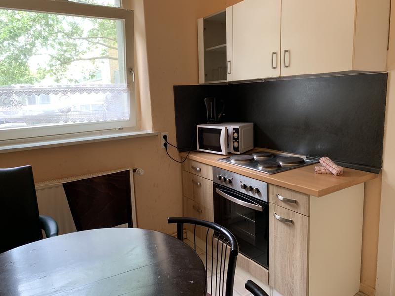 Kleine helle Küchenzeile mit einem dunklen Esstisch und Stühlen