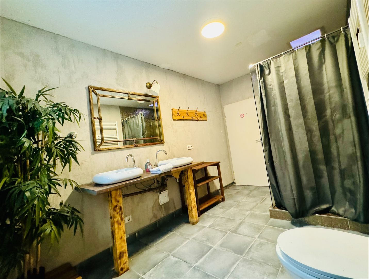 Badezimmer mit zwei Waschbecken auf Holzkonsole, großem Spiegel und Pflanze