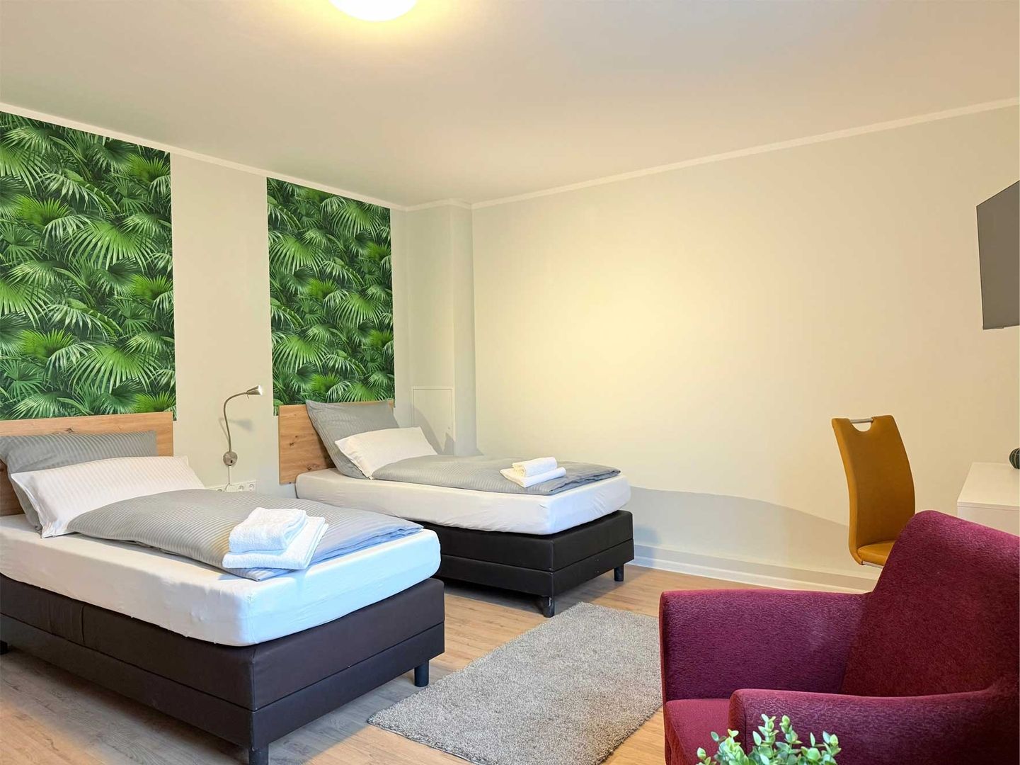 Modernes Zweibettzimmer mit Wandgestaltung hinter den Betten