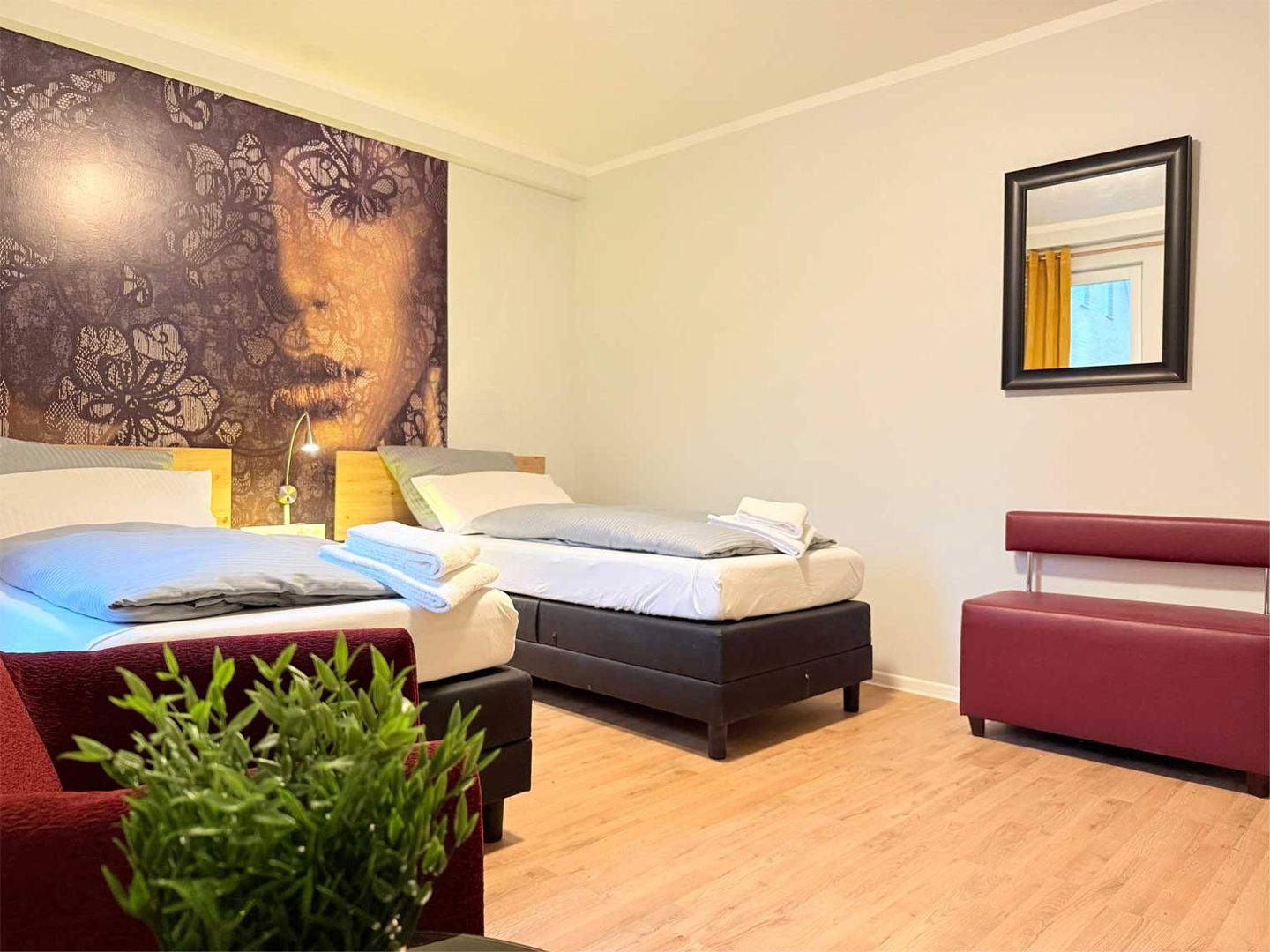 Zweibettzimmer mit großem abstrakten Menschengesicht an der Wand